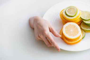 Dilimlenmiş limon, limon ve portakallı süt banyosunun kadın eli görüntüsü