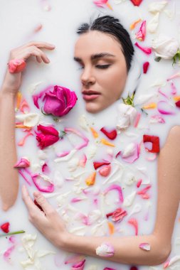 Şehvetli bir kadın süt ve gül yapraklarıyla banyo yapıyor.
