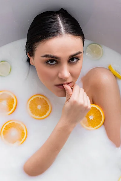 Mulher Sensual Banho Leite Com Cítricos Tocando Lábios Enquanto Olha — Fotografia de Stock