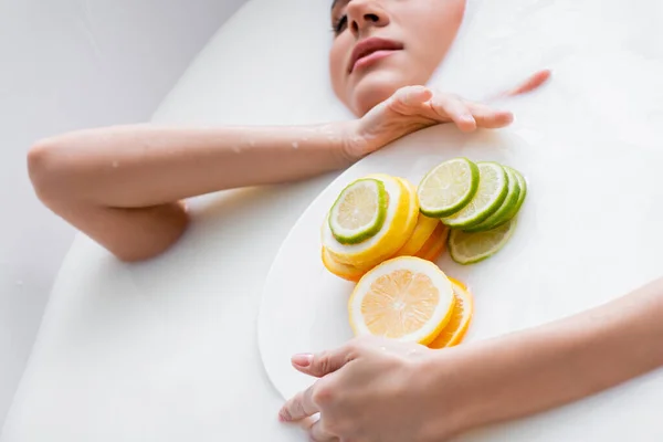 Plato Con Cítricos Frescos Rodajas Manos Una Mujer Bañándose Leche — Foto de Stock