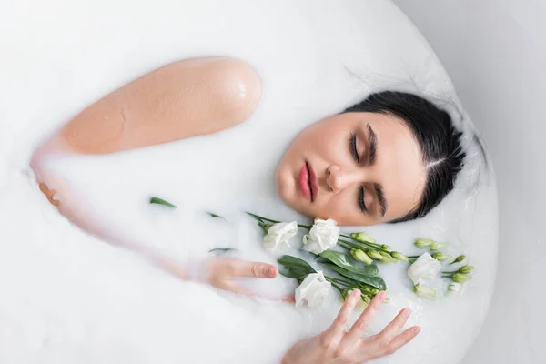 ミルク風呂でイースタスの花でリラックスしてる可愛い女 — ストック写真