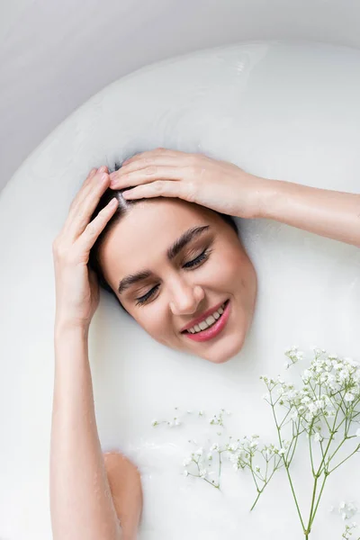 石鹸フラワーでミルクを飲みながら髪に触れる笑顔の女性 — ストック写真