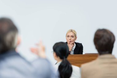 blonde speaker listening to blurred businessman asking question during seminar clipart