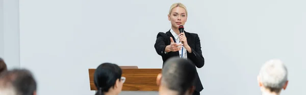 Blondynka Głośnik Trzymając Mikrofon Wskazując Uczestników Podczas Seminarium Baner — Zdjęcie stockowe