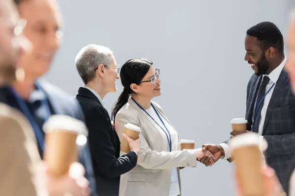 コーヒーブレイク中に同僚の近くで握手をする多民族経営者の選択的焦点 — ストック写真