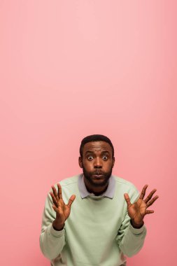 Korkak Afrikalı Amerikalı adam pembe kameraya bakıyor. 