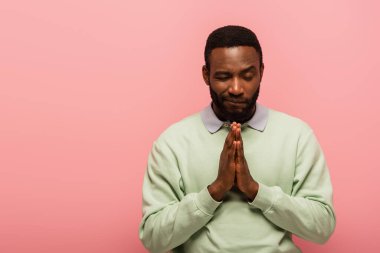 Pembe üzerinde dua eden Afrika kökenli Amerikalı bir adam. 