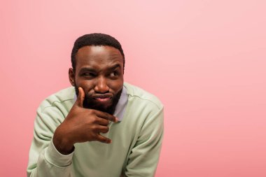 Tricky african american man looking away isolated on pink  clipart