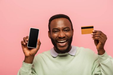Pozitif Afro-Amerikalı adam elinde akıllı telefon ve kredi kartı tutuyor. 