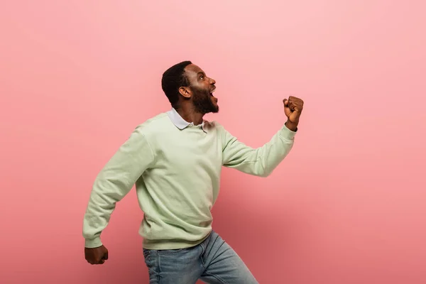 側ビューの興奮アフリカ系アメリカ人男性ショーええジェスチャー上のピンクの背景 — ストック写真