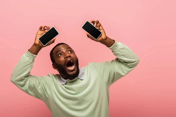 Hombre Afroamericano Asustado Sosteniendo Teléfonos Celulares Con Pantalla Blanco Aislado — Foto de Stock