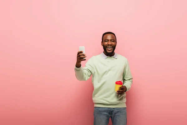 Pozitív Afro Amerikai Férfi Kezében Mobiltelefon Kávé Menni Rózsaszín Háttér — Stock Fotó