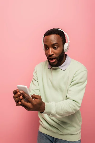 Opgewonden Afrikaans Amerikaanse Man Hoofdtelefoon Met Behulp Van Smartphone Geïsoleerd — Stockfoto