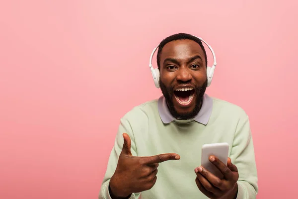 Uomo Afroamericano Stupito Cuffia Che Punta Smartphone Isolato Rosa — Foto Stock