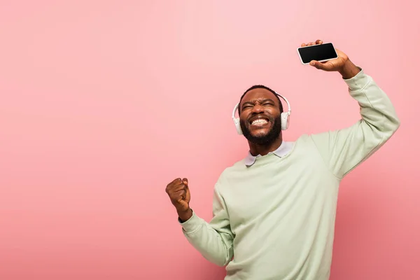 Afrikai Amerikai Férfi Fülhallgató Gazdaság Smartphone Mutatja Igen Gesztus Elszigetelt — Stock Fotó