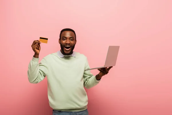 Amazed African American Man Showing Credit Card While Holding Laptop — Stock Photo, Image