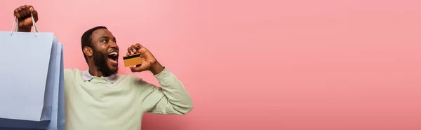 Дивовижний Афроамериканський Чоловік Кредитною Карткою Покупками Дивлячись Ізольовано Рожевому Банер — стокове фото