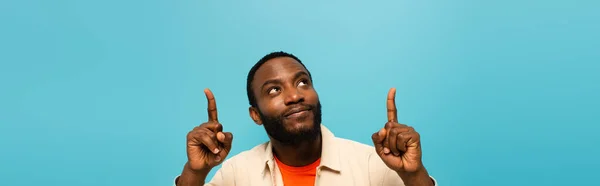 Sorridente Afro Americano Apontando Para Cima Com Dedos Isolados Azul — Fotografia de Stock