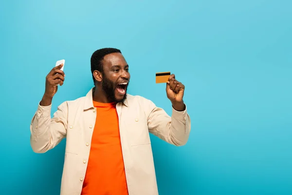 Excited African American Man Holding Credit Card Mobile Phone Blue — Stock Photo, Image