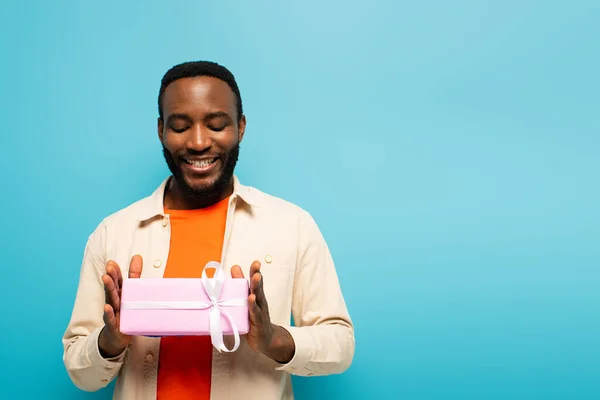 Pleased African American Man Holding Gift Box Isolated Blue — Stock Photo, Image