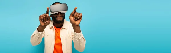Afrikaans Amerikaanse Man Gaming Headset Wijzen Met Vingers Geïsoleerd Blauw — Stockfoto