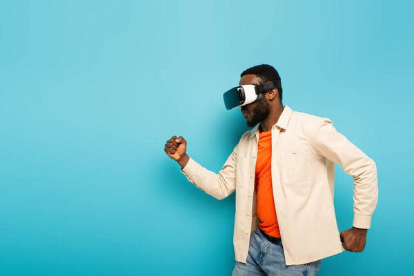 african american man dancing in vr headset on blue background