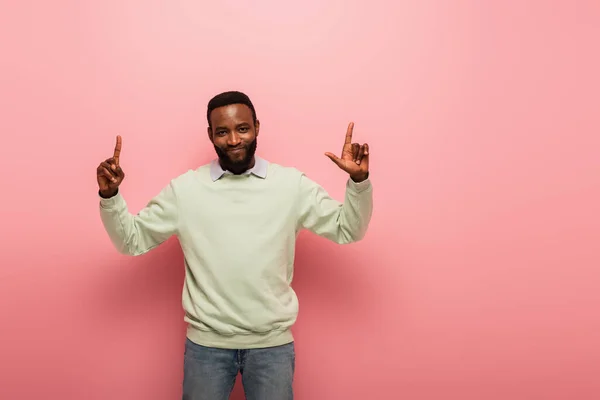 Веселый Африканский Американец Улыбается Камеру Показывает Пальцами Розовом Фоне — стоковое фото
