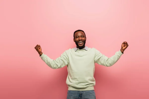 興奮したアフリカ系アメリカ人男性がピンクの背景のカメラで笑顔を見せながら — ストック写真