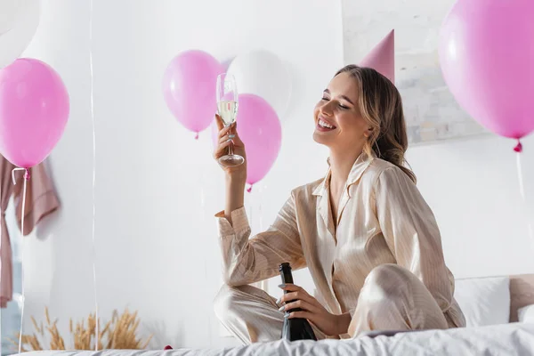 Fröhliche Frau Mit Champagner Feiert Geburtstag Neben Luftballons Schlafzimmer — Stockfoto