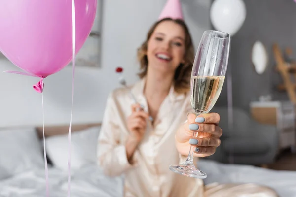 Glas Champagne Hand Van Wazige Vrouw Feestmuts Bij Ballonnen Slaapkamer — Stockfoto