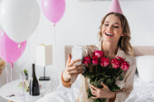 Usmívající se žena brát selfie na smartphone a držení růží během narozeninové oslavy