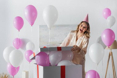 Parti şapkalı heyecanlı kadın evinde balonlarla açılış hediyesi. 