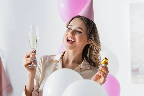 Glimlachende Vrouw Feestmuts Met Hoorn Champagne Bij Ballonnen Thuis — Stockfoto
