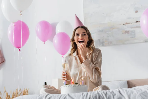 Glada Kvinna Håller Glas Champagne Nära Födelsedagstårta Med Ljus Sängen — Stockfoto