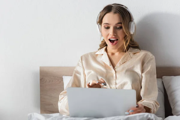 Excited Woman Headphones Looking Blurred Laptop Bed — Stock Photo, Image