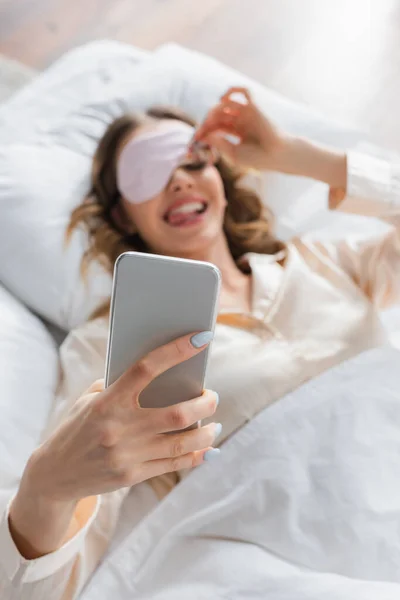 Smartphone Kezében Elmosódott Alvó Maszkot Ágyban — Stock Fotó