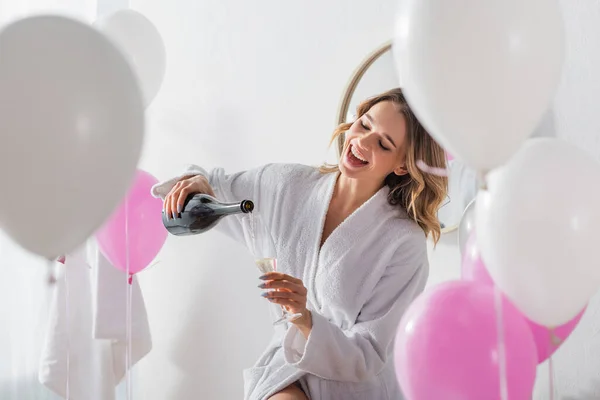 Vrolijke Vrouw Badjas Gieten Champagne Buurt Ballonnen Badkamer — Stockfoto