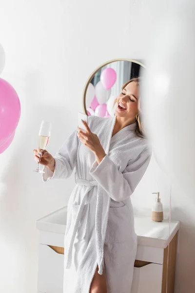 Lächelnde Frau Bademantel Fotografiert Champagner Neben Luftballons Badezimmer — Stockfoto