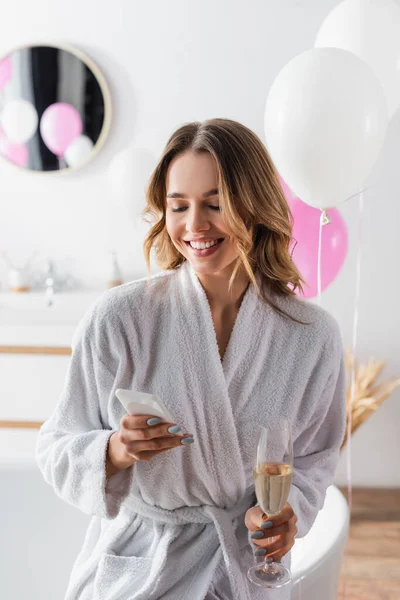 Mujer Sonriente Albornoz Usando Smartphone Sosteniendo Champán Baño — Foto de Stock