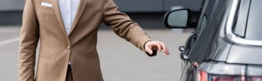 cropped view of man in beige jacket reaching car door, banner 