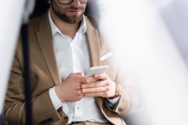 cropped view of bearded man chatting on smartphone in car 