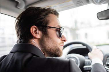 bearded bodyguard in sunglasses driving modern automobile 