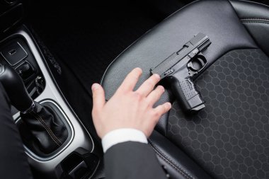 top view of bodyguard reaching gun on seat of modern automobile  clipart