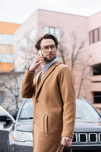 Young Man Glasses Coat Talking Smartphone — Stockfoto