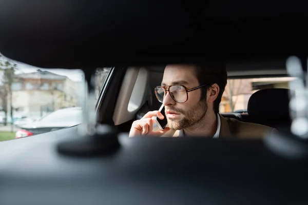 戴眼镜的男人开车在智能手机上说话 — 图库照片