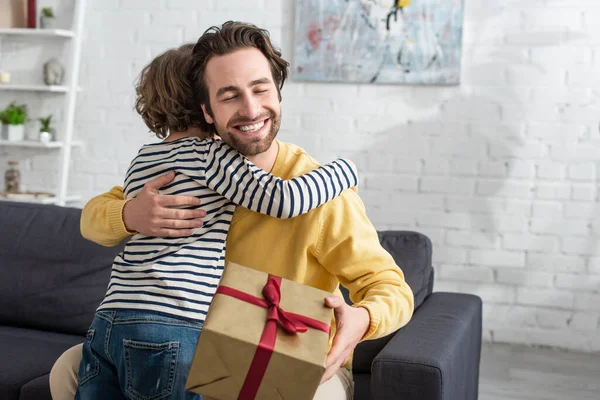 Sorrindo Homem Abraçando Filho Segurando Presente Casa — Fotografia de Stock