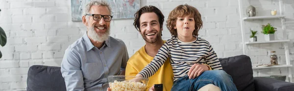 映画の間に息子と子供の近くにポップコーンを持っている笑顔男 バナー — ストック写真