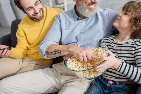 Sonriente Niño Sosteniendo Palomitas Maíz Cerca Abuelo Padre Con Mando — Foto de Stock