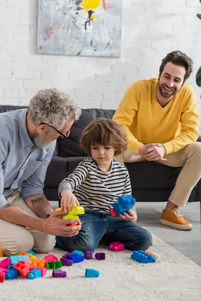 Abuelo Jugando Bloques Construcción Con Nieto Cerca Sonreír Hijo Sofá —  Fotos de Stock