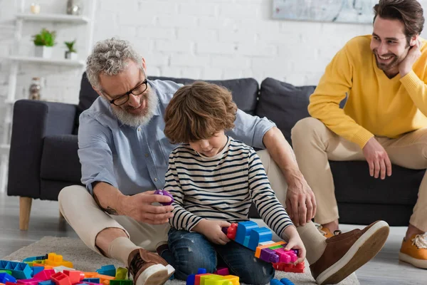 Avô Jogando Blocos Construção Com Criança Chão Perto Filho Sofá — Fotografia de Stock